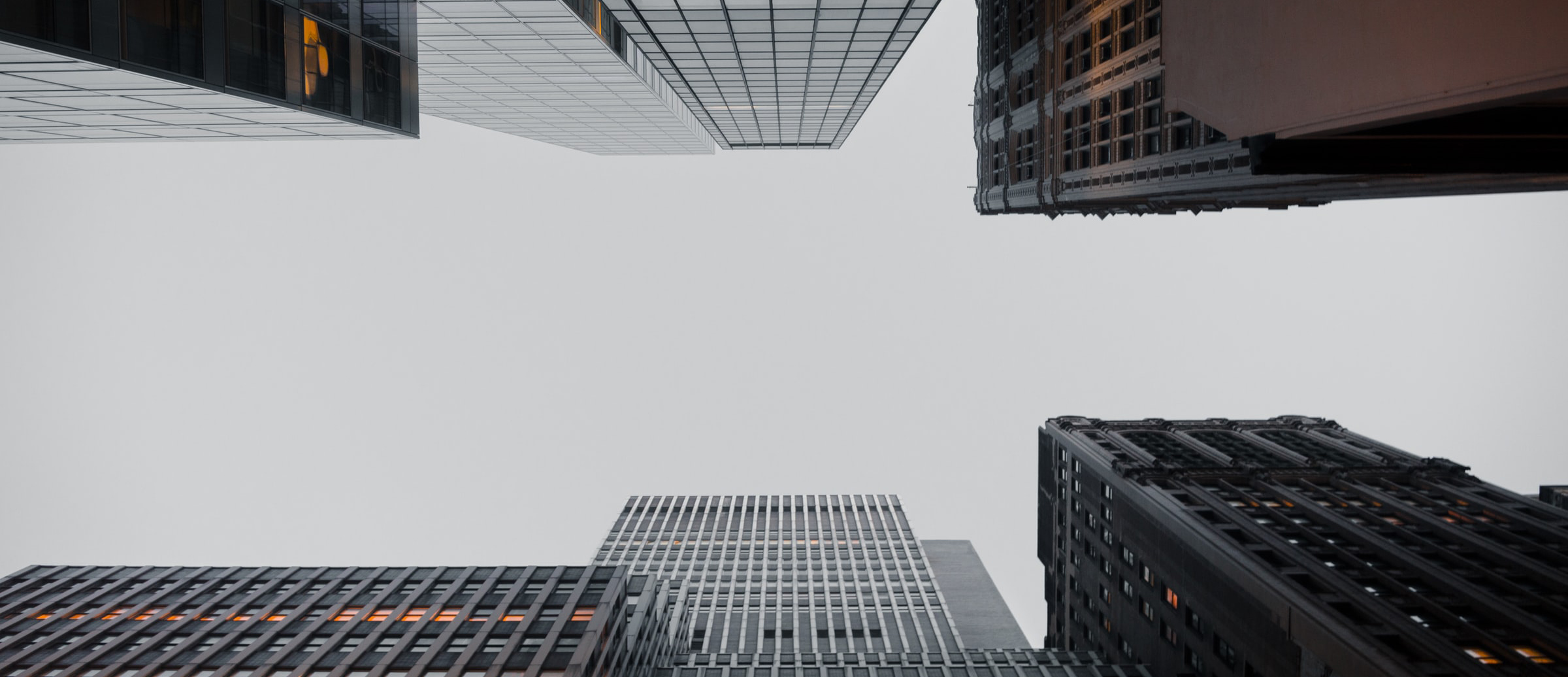 Céu cinza emoldurado por altos prédios modernos e antigos.