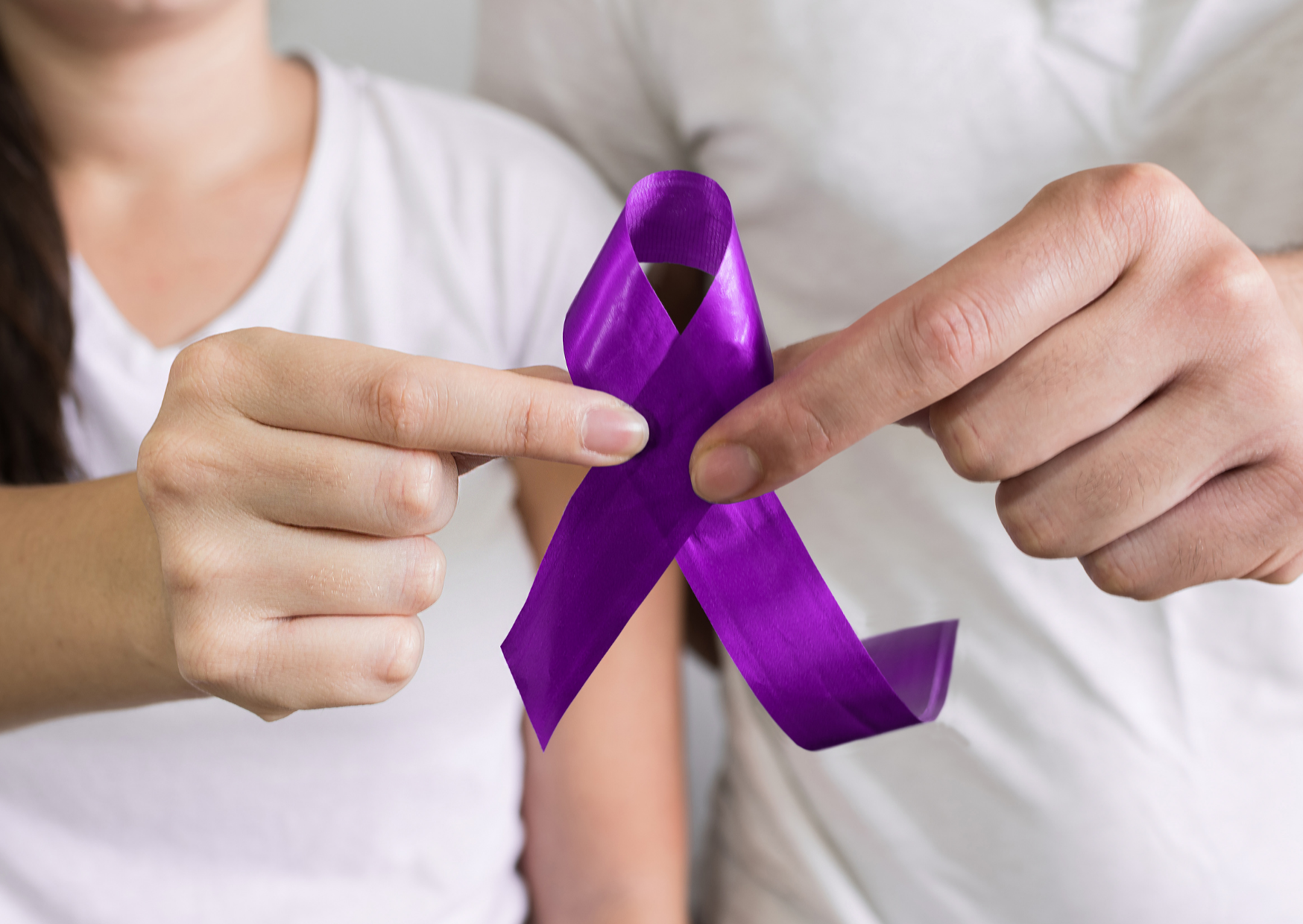 Mão e um homem e uma mulher segurando laço roxo